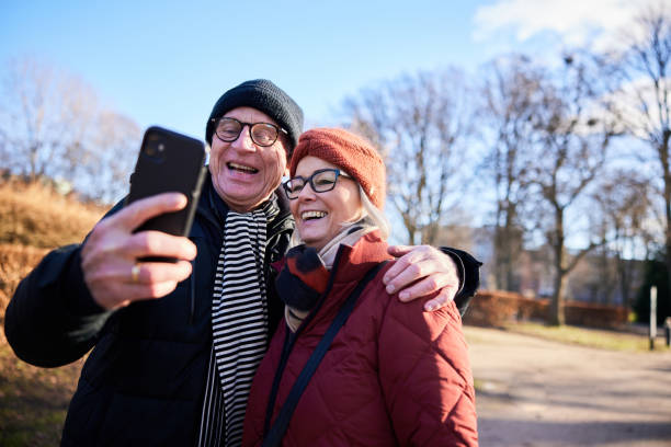 istock Senior couple laughing while taking a selfie in a park in winter 1486074671
