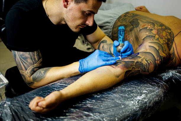 istock Man is tattooing a man's arm in tattoo studio 1486075113
