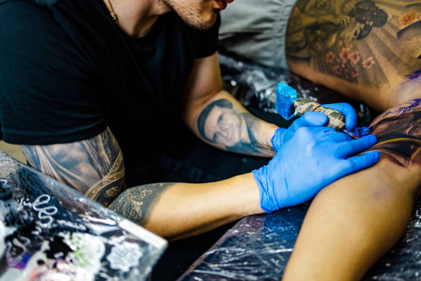 istock Tattoo expert tattooing male customer's arm in studio 1486075724