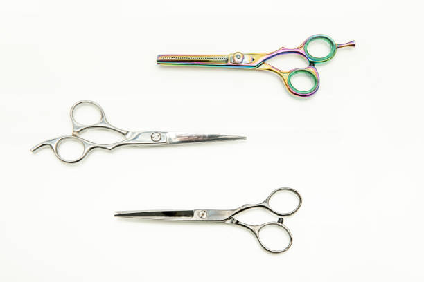 Various types of barber scissors on a white wooden surface viewed from the top