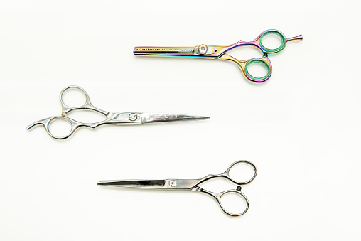 Various types of barber scissors on a white wooden surface viewed from the top
