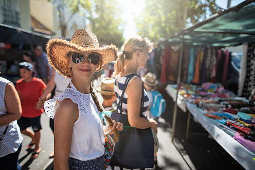 Tourist family buying souvenirs on flea market in Andalusia, Spain. Teenage girl is smiling at the camera.\nNikon D810