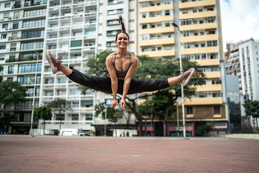 Young woman jumping doing the splits outdoors