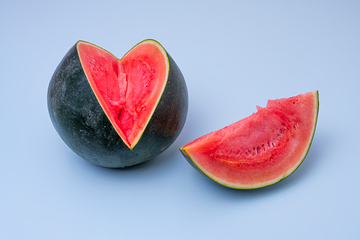 Watermelon with a red cut slice without seeds on blue background.