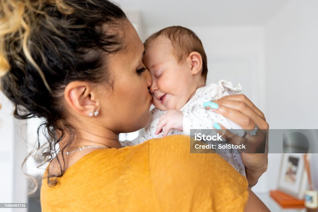 I Will Always Love You Waist-up shot of a mid-adult woman holding her newborn daughter. The mother is wearing casual clothing and kissing her daughter both closing their eyes. Life Events Stock Photo