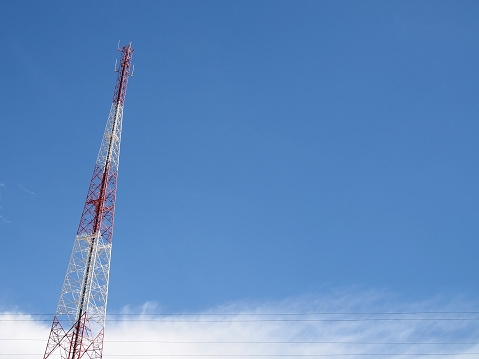 red and white high steel framework of telecommunication tower with clear blue sky and cloud with copy space