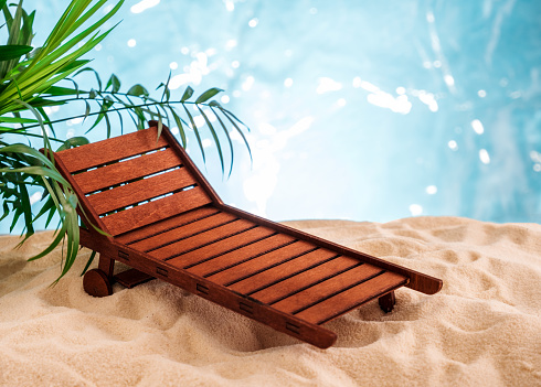 Miniature wooden sunbed on a sandy beach. Summer project stand mockup.
