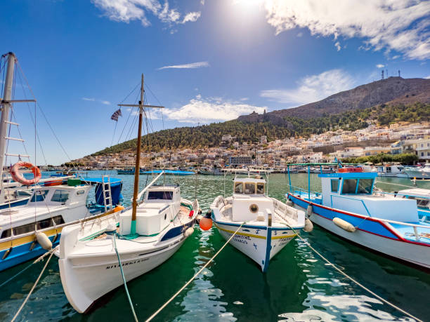 Beautiful summer vacation seascape, little fisher towns, tourist sightseeing ships, fishing boats, whitewashed houses, blue window frames and national flag of Greece. Blue sky, sea background with copy space. Sales, marketing poster template