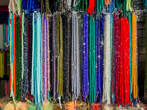 DYI concept: Many hanging colorful shiny crystal jewelry beads, selective focus. Beautiful handicrafts background with copy space