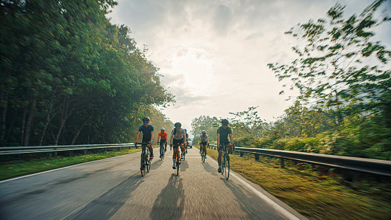 Asian Chinese Cyclist team cycling in rural area during weekend morning backlit warm light