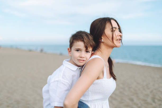 istock Mother and son walking at the beach 1486093108