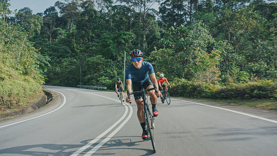 Asian Chinese male cyclist cruising downhill enjoying weekend cycling at rural scene