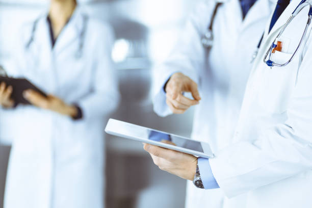 istock Group of unknown doctors use a computer tablet to check up some medical names records, while standing in a hospital office. Physicians ready to examine and help patients. Medical help, insurance in health care, best desease treatment and medicine concept 1486093215