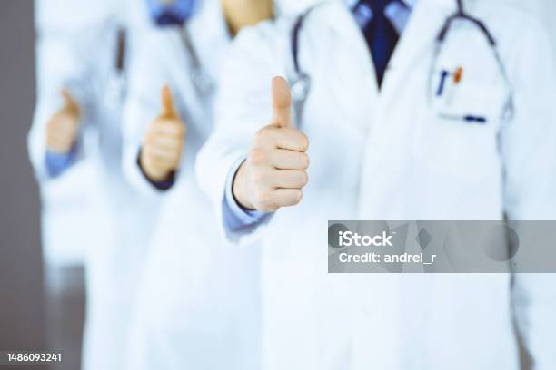 Group Of Unknown Doctors Stand As A Team With Thumbs Up In A Hospital Office Physicians Ready To Examine And Help Patients Medical Help Insurance In Health Care Best Desease Treatment And Medicine Concept Stock Photo - Download Image Now