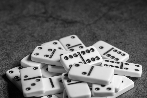 several tiles of classic dominoes on a dark background , black and white photo