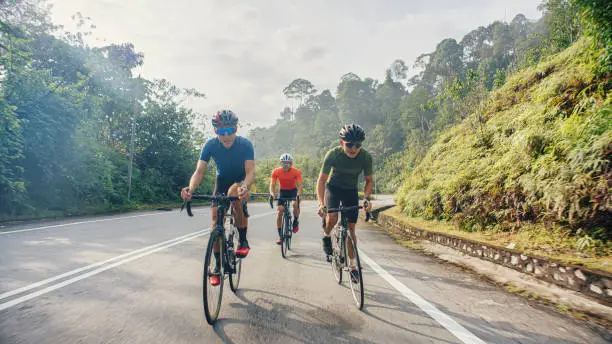 Photo of Asian Chinese male cyclist cruising downhill enjoying weekend cycling at rural scene