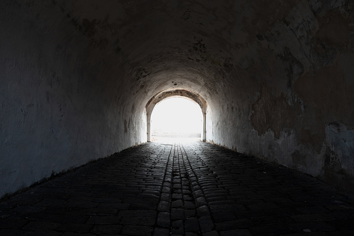 Perspective view of an empty dark tunnel with bright glowing end