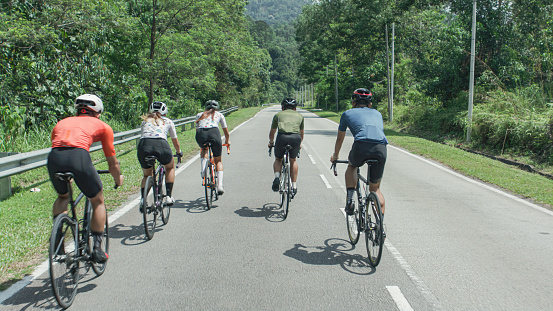 Rear view Asian Chinese Cyclist team moving past cycling in rural area during weekend morning