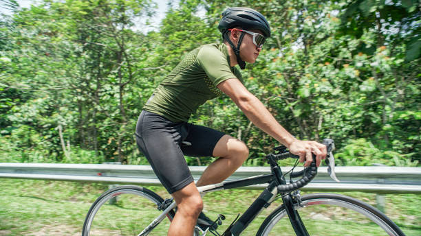 暑い太陽の下で田舎のシーンでサイクリングするアジアの中国人サイクリストのサイドビュー - cycling shorts ストックフォトと画像