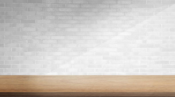 istock empty minimal table for product displayed. oak wooden table at foreground on white brick background with soft light beam. elegant scene for business advertising. 1486096099