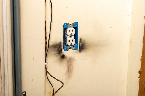 Electrical outlet on wall with burn marks after surge strike.