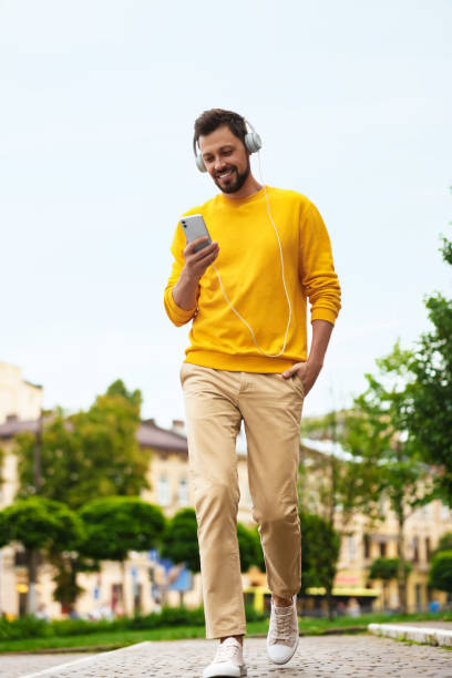 bel homme avec smartphone et écouteurs marchant dans la rue de la ville - headphones relaxation outdoors caucasian photos et images de collection