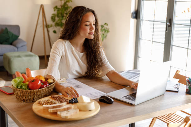 istock Diligent young female nutritionist sitting at her desk and using laptop 1486105557