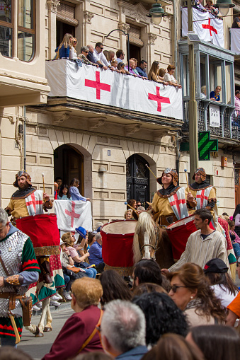 04-22-2023, Alcoy, Spain. Traditional Moors and Christians festivals in Alcoy. Facades adorned with Saint George flags, people and the start of the parade