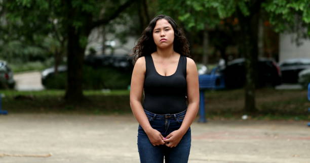 Hispanic girl standing outside looking at camera. Latina young woman serious expression stock photo