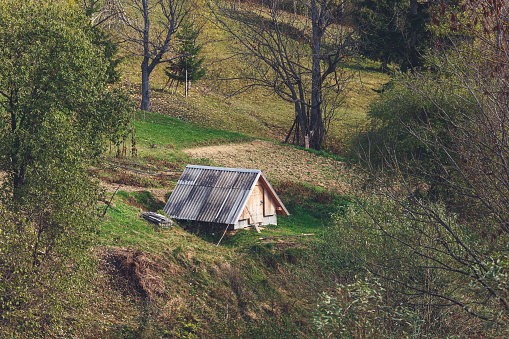 Small wooden house or barn on hillside.