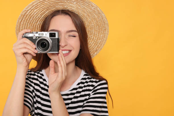 istock Young woman with camera taking photo on yellow background, space for text. Interesting hobby 1486113499