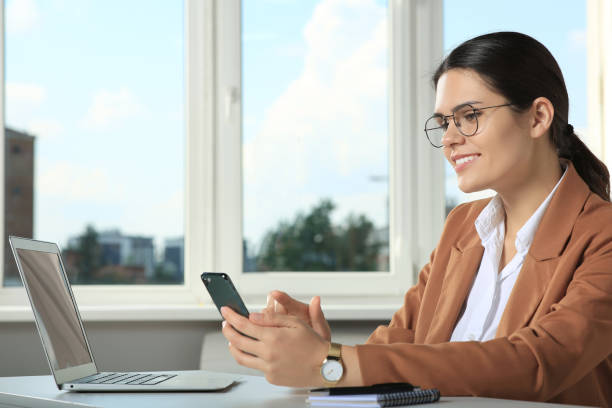 istock Young woman using smartphone at table in office 1486114102