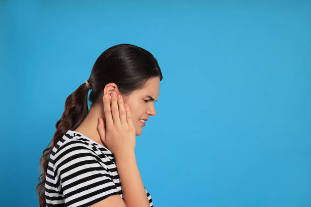 istock Young woman suffering from ear pain on light blue background, space for text 1486114105