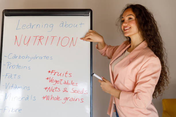 istock Professional female nutritionist standing by a whiteboard, holding a presentation on basics of nutrition 1486114110