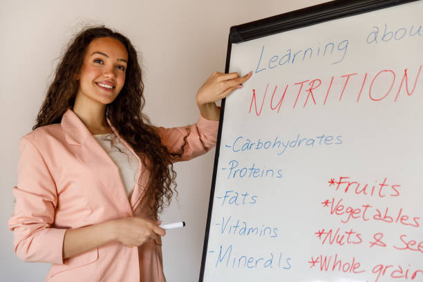 istock Professional female nutritionist standing by a whiteboard, holding a presentation on basics of nutrition 1486114121