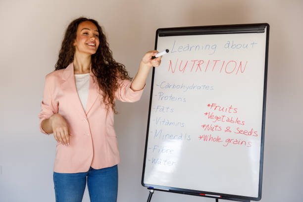 istock Professional female nutritionist standing by a whiteboard, holding a presentation on basics of nutrition 1486114748