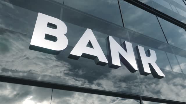 Bank sign on glass building. Mirrored sky and city on modern facade. Business and finance concept