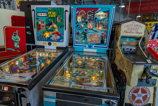 San Francisco, United States - November 25, 2022: A picture of some retro arcade games, including two pinball machines and a shooter machine.