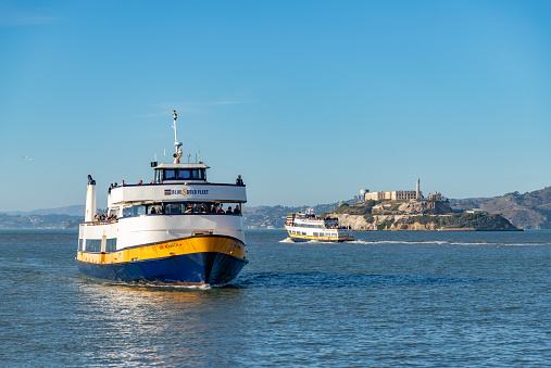 San Francisco, United States - November 25, 2022: A picture of two Blue and Gold cruise boats in the San Francisco Bay, with Alcatraz Island at the far right.