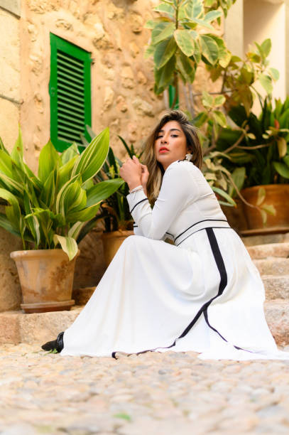istock Model sitting on stone stairs posing in white elegant dress 1486118627