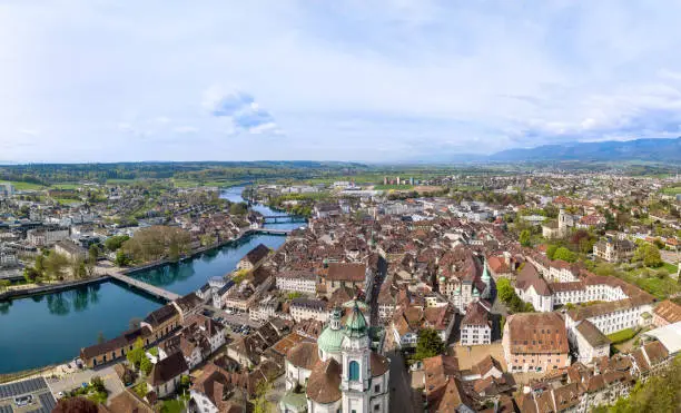 Panorama of aerial views of the old town of Solothurn city with St. Ursus Cathedral - a Swiss heritage site of national significance - at the foreground and the Aare River on the left.