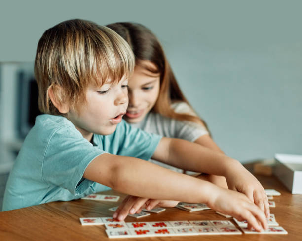 child girl boy childhood kid brother sister game card logic find quiz sorting education learning game puzzle attention board game Portrait of brother and sister having fun together playing  game of cards matching logic or board game at home family playing card game stock pictures, royalty-free photos & images