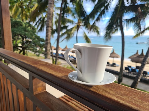 Cup of tropical coffee on beach balcony. Paradise island and morning in Asia