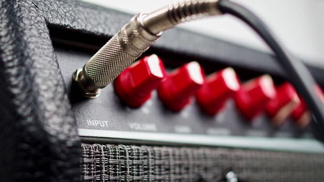 Hand put a sound cable on an Amplifier with red buttons, closeup shot