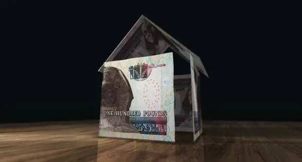 Egyptian Pound 100 EGP money banknotes paper house on the table. Egypt currency notes 3D illustration concept of home mortgage loan, costs, liabilities and real estate financing.