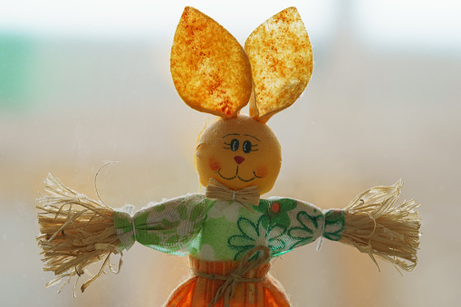Paper figurine of funny rabbit girl. She is smiling.  Concept of happiness, beauty, good mood. Front view. Bright colors (golden, green, red). Light bokeh