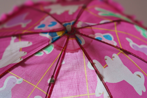 Child is hiding under umbrellas. Lifestyle concept. The surface of the pink children's umbrella. You can alco use it for walking under the sun