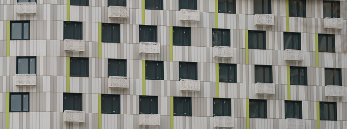 Texture, design and right geometry of new modern residetial building exterior in the city Moscow in spring day. Modern construction. Close up photography. Beige white, green, colors in the design