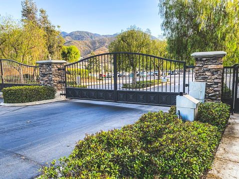 Stone archway and wrought iron gate in front of Spanish architectural designed home.