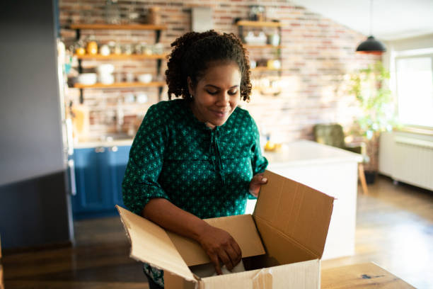 istock Young woman opening up a box she received in the mail 1486136896